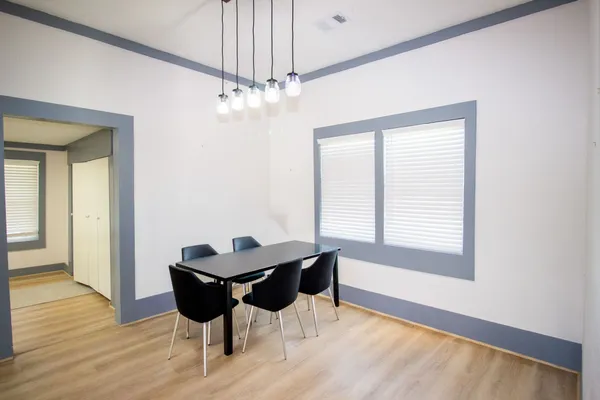 a dining room with chandelier and wooden floor