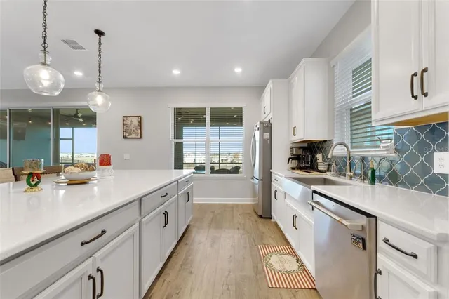 a kitchen with stainless steel appliances kitchen island granite countertop a dining table chairs refrigerator and microwave