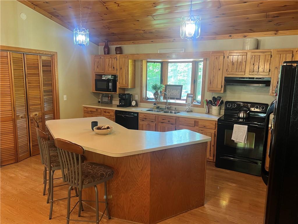 121 Pitts Road Jamestown, PA 16134 - Photo 15 of 28 a kitchen with a stove a sink a kitchen island with chairs and wooden floor