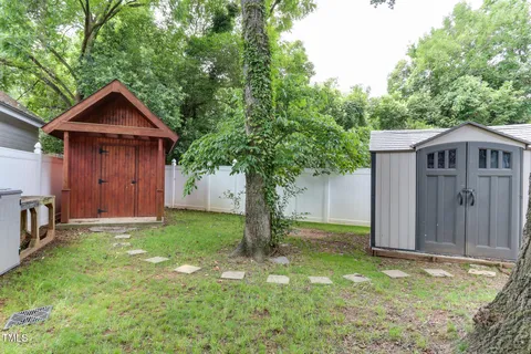 a backyard of a house with a large tree and wooden fence