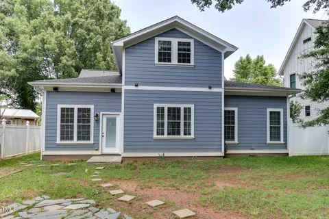 a view of a house with a yard and large trees