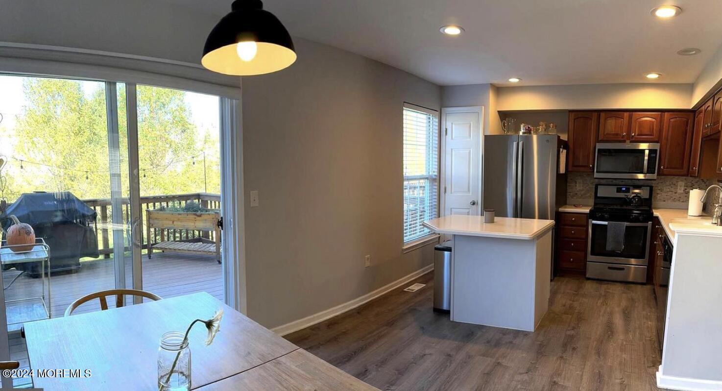 52 Saxton Road Farmingdale, NJ 07727 - Photo 28 of 52 a kitchen with stainless steel appliances granite countertop a stove a refrigerator a sink a dining table and chairs with wooden floor
