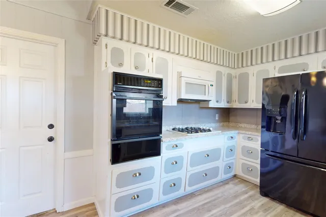 a kitchen with stainless steel appliances white cabinets and wooden floor