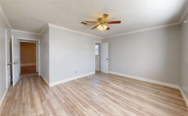 a view of an empty room with wooden floor and a ceiling fan
