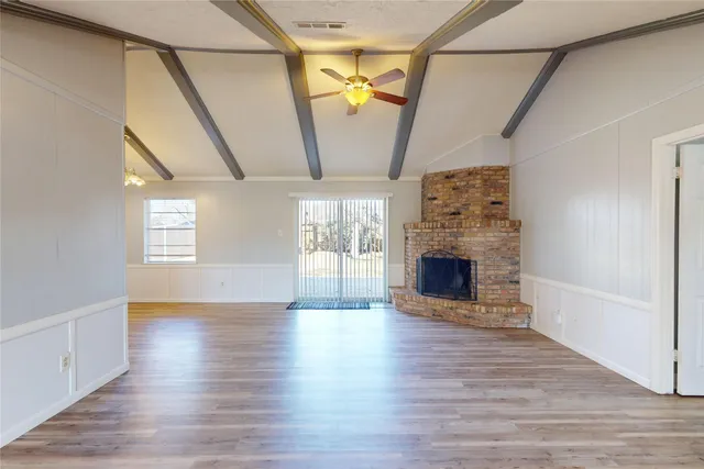 a view of a livingroom with wooden floor and a fireplace