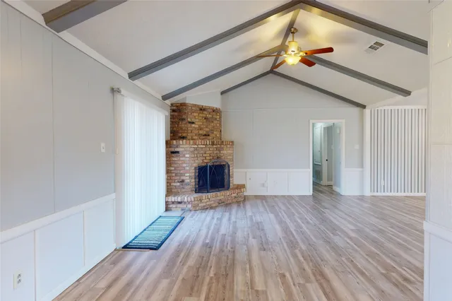 a view of empty room with wooden floor and fireplace