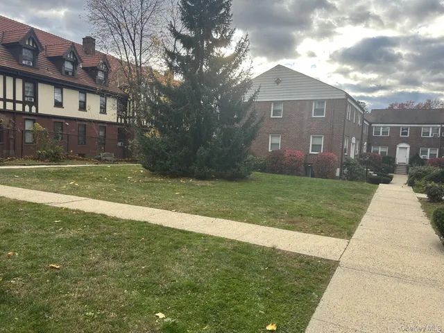 a view of a brick house next to a yard with big trees