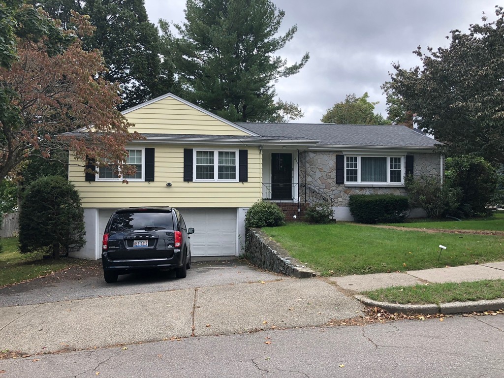 a front view of a house with a garden and trees