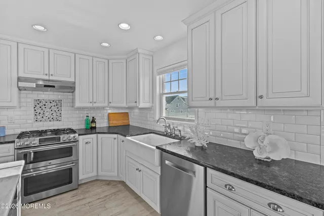 a kitchen with granite countertop white cabinets and stainless steel appliances