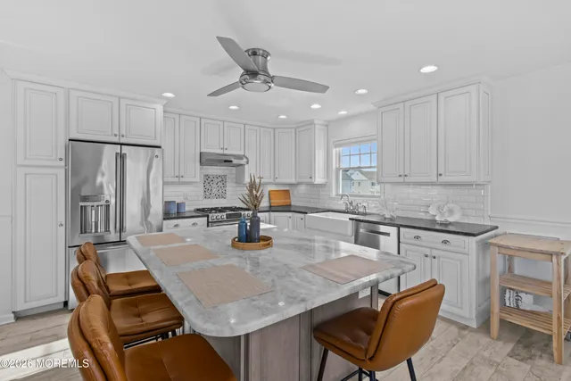 a kitchen with stainless steel appliances granite countertop a sink a stove a refrigerator cabinets and chairs