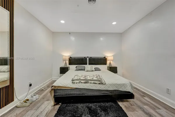 a view of a bedroom with a bed and wooden floor