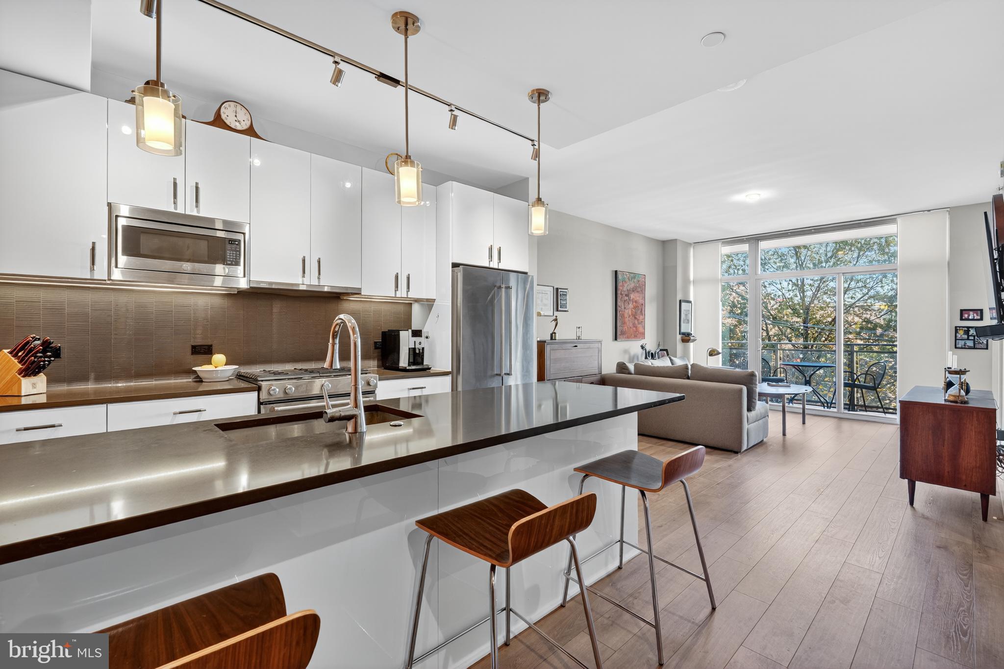 a kitchen with stainless steel appliances granite countertop a refrigerator a sink dishwasher a stove kitchen island with chairs and wooden floor
