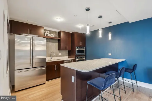 a kitchen with stainless steel appliances granite countertop a refrigerator a sink dishwasher a stove with wooden floor