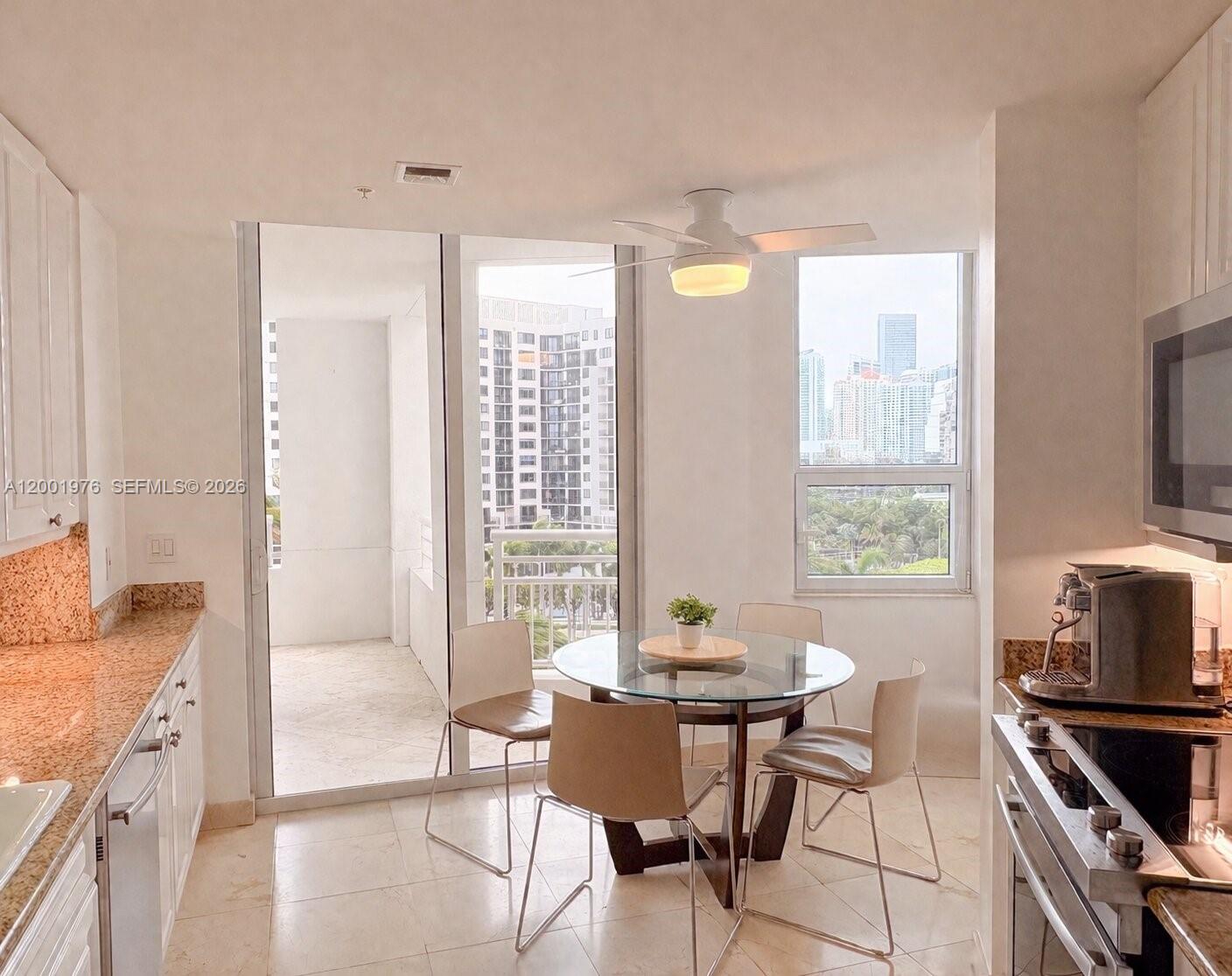 848 Brickell Key Drive, Unit 905 Miami, FL 33131 - Photo 17 of 28 a kitchen with granite countertop a stove a sink dining table and chairs