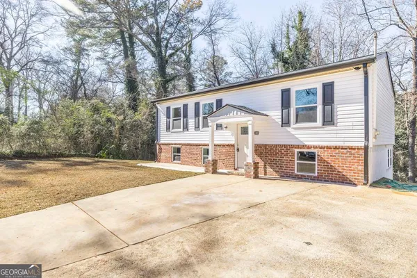 a view of house with yard and trees in the background