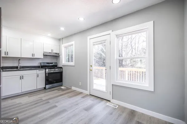 a kitchen with granite countertop a stove a sink and a refrigerator
