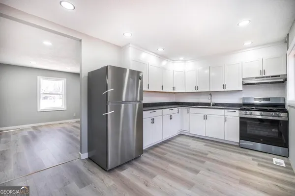 a kitchen with granite countertop a refrigerator and a stove top oven