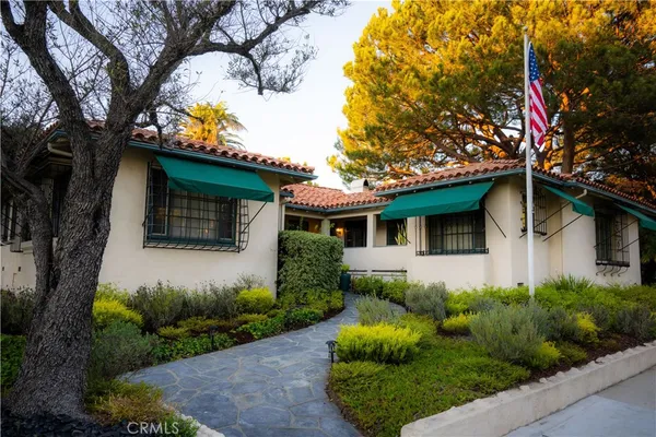 a front view of a house with a yard and potted plants