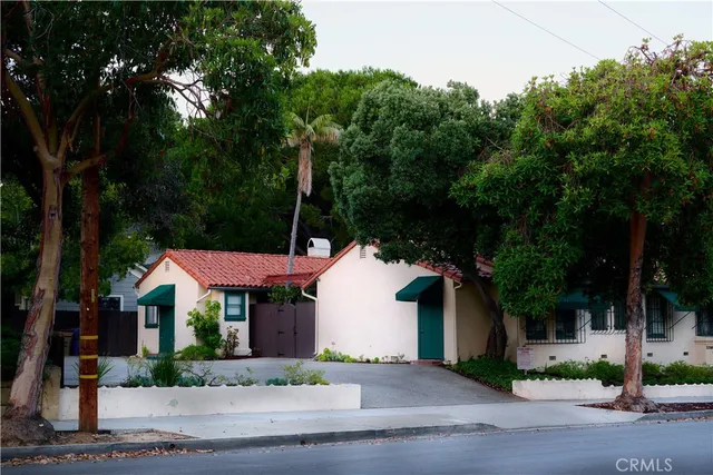 a front view of a house with a garden and tree