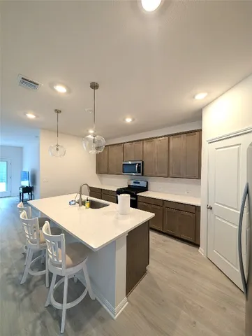 a kitchen with a refrigerator a stove a sink dishwasher with a dining table and chairs