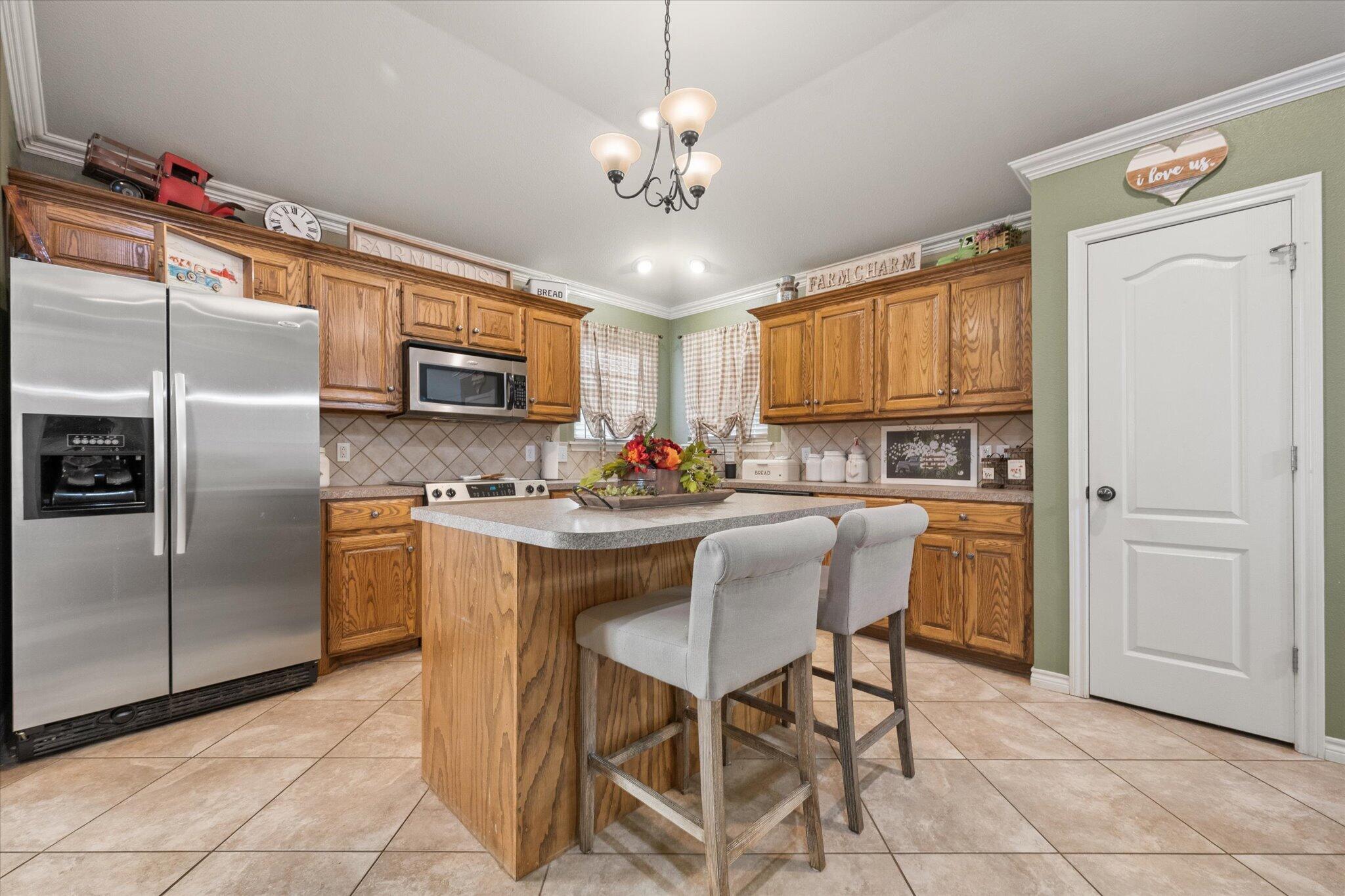 5838 101st Street Lubbock, TX 79424 - Photo 19 of 37 a kitchen with stainless steel appliances granite countertop a refrigerator a stove a sink dishwasher and a refrigerator with wooden cabinets