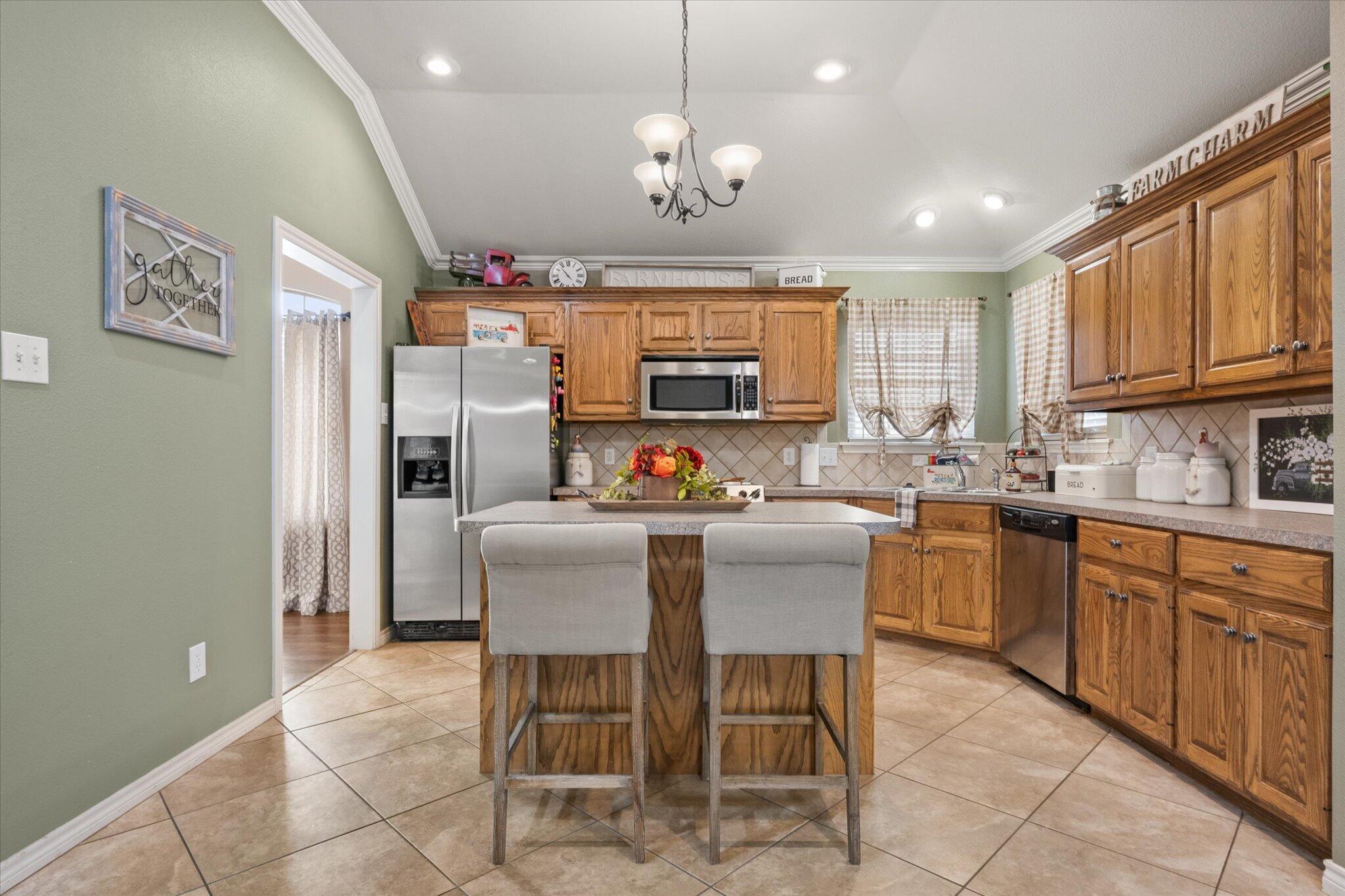 5838 101st Street Lubbock, TX 79424 - Photo 21 of 37 a kitchen with stainless steel appliances granite countertop a refrigerator a sink dishwasher a dining table and chairs with wooden floor