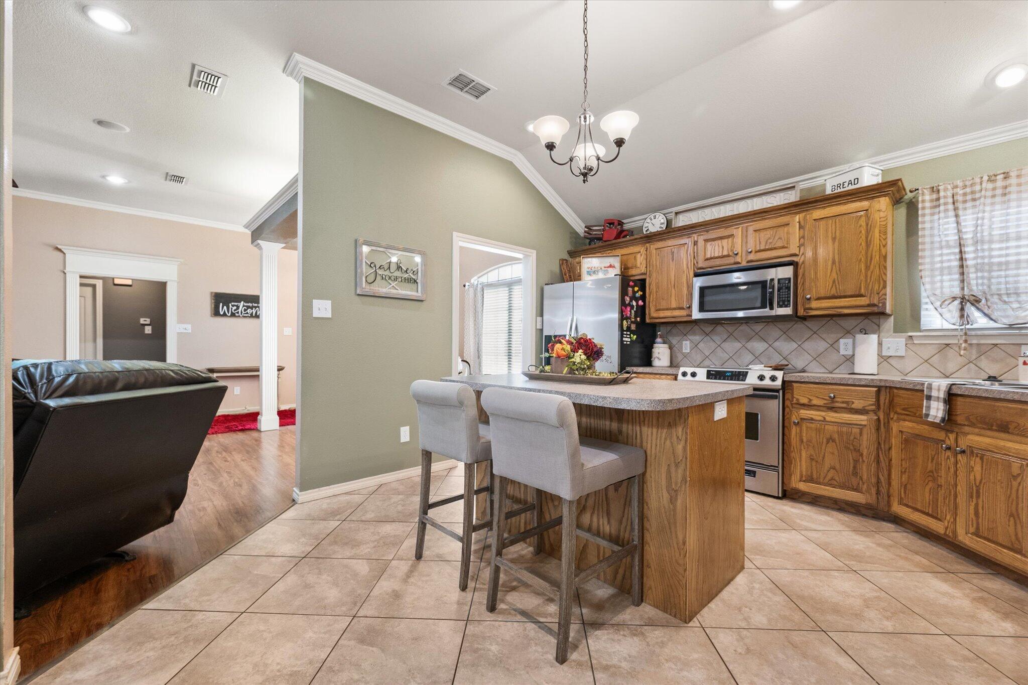5838 101st Street Lubbock, TX 79424 - Photo 22 of 37 a kitchen with stainless steel appliances granite countertop a stove top oven a sink dishwasher a dining table and chairs with wooden floor