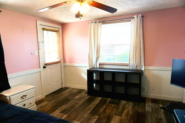 a view of an empty room with a window and wooden floor