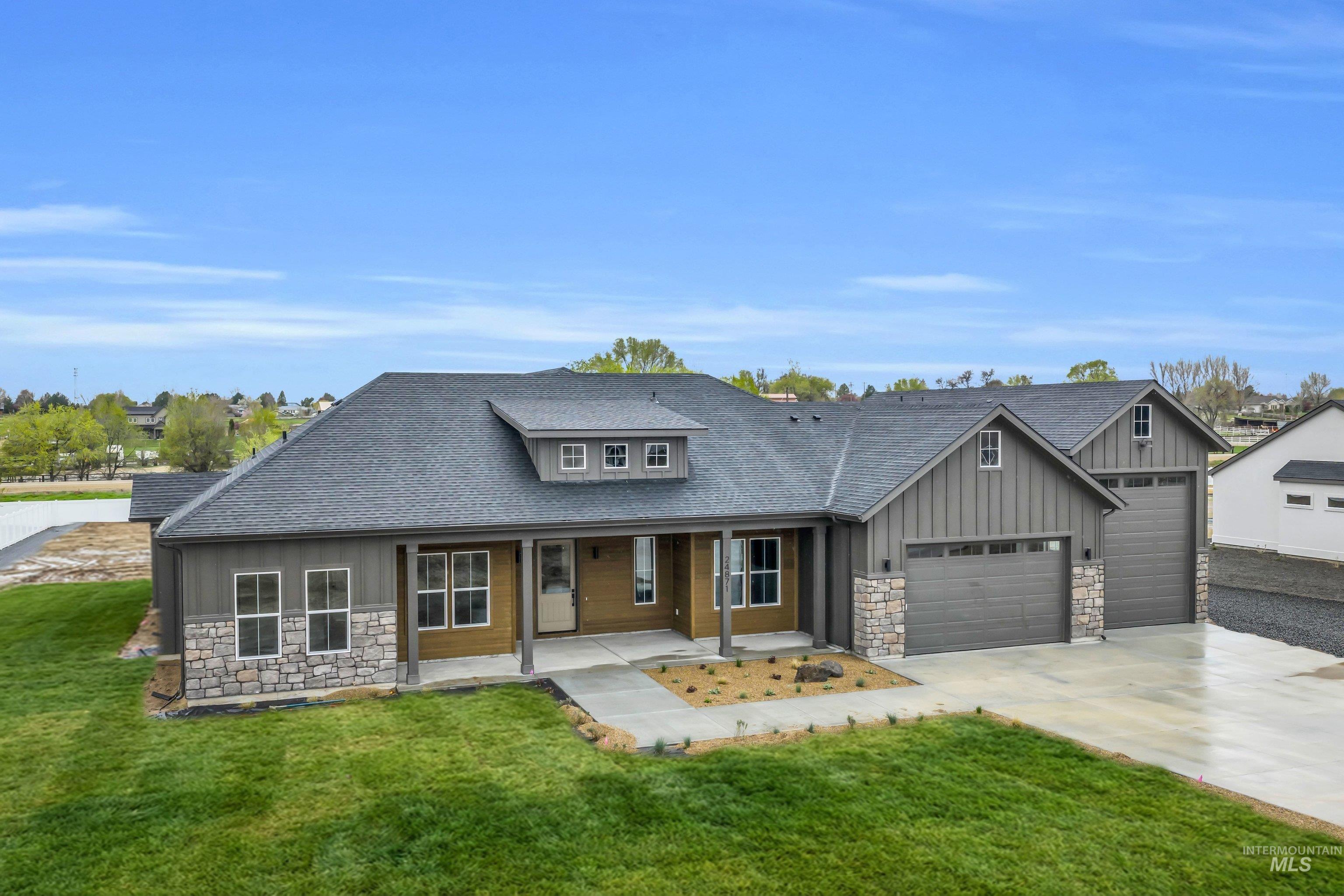 Craftsman house featuring stone siding, a shingled roof, board and batten siding, covered porch, and concrete driveway