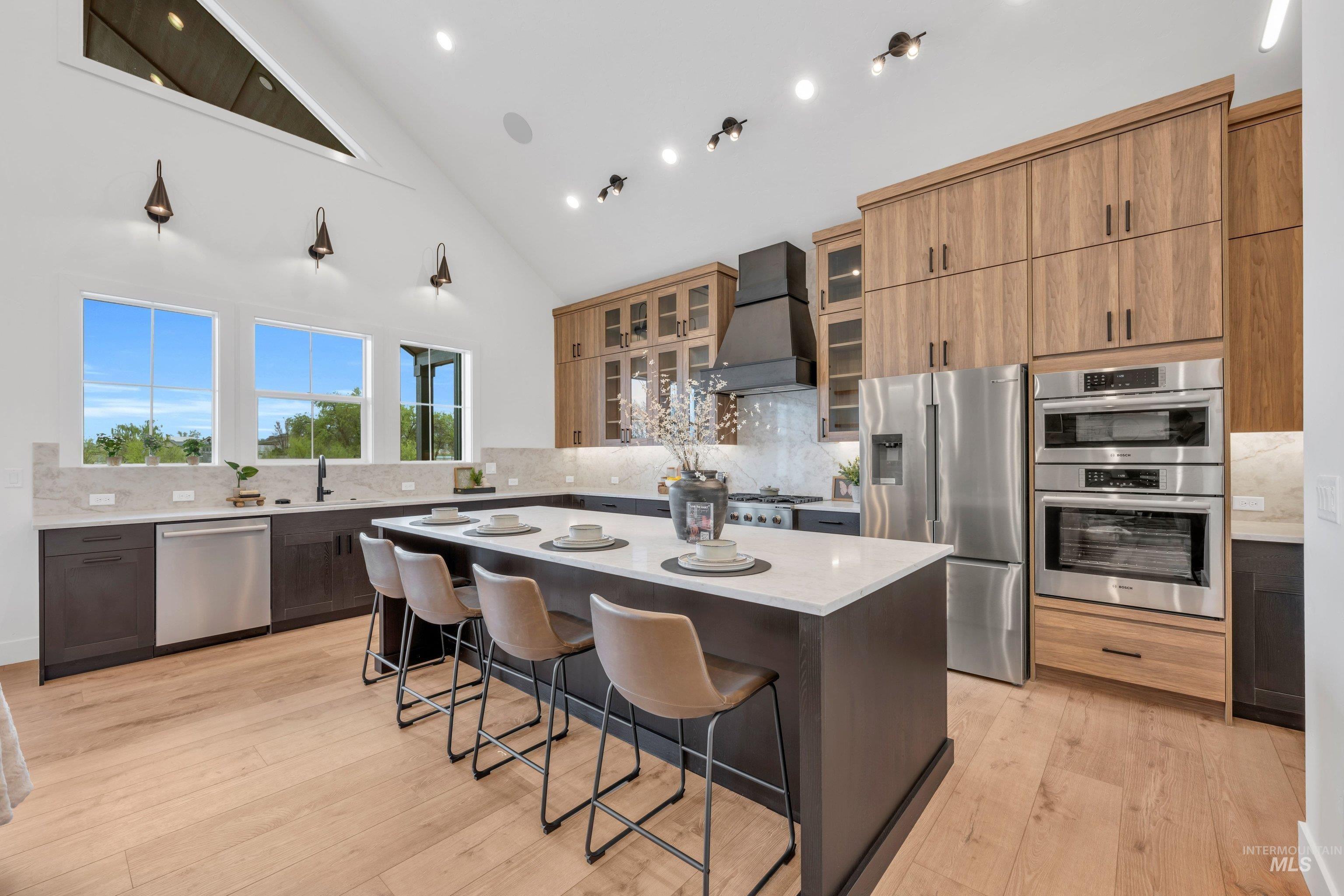 24871 Ardmore Court Caldwell, ID 83607 - Photo 11 of 44 Kitchen featuring a center island, stainless steel appliances, a breakfast bar area, light stone counters, and glass insert cabinets