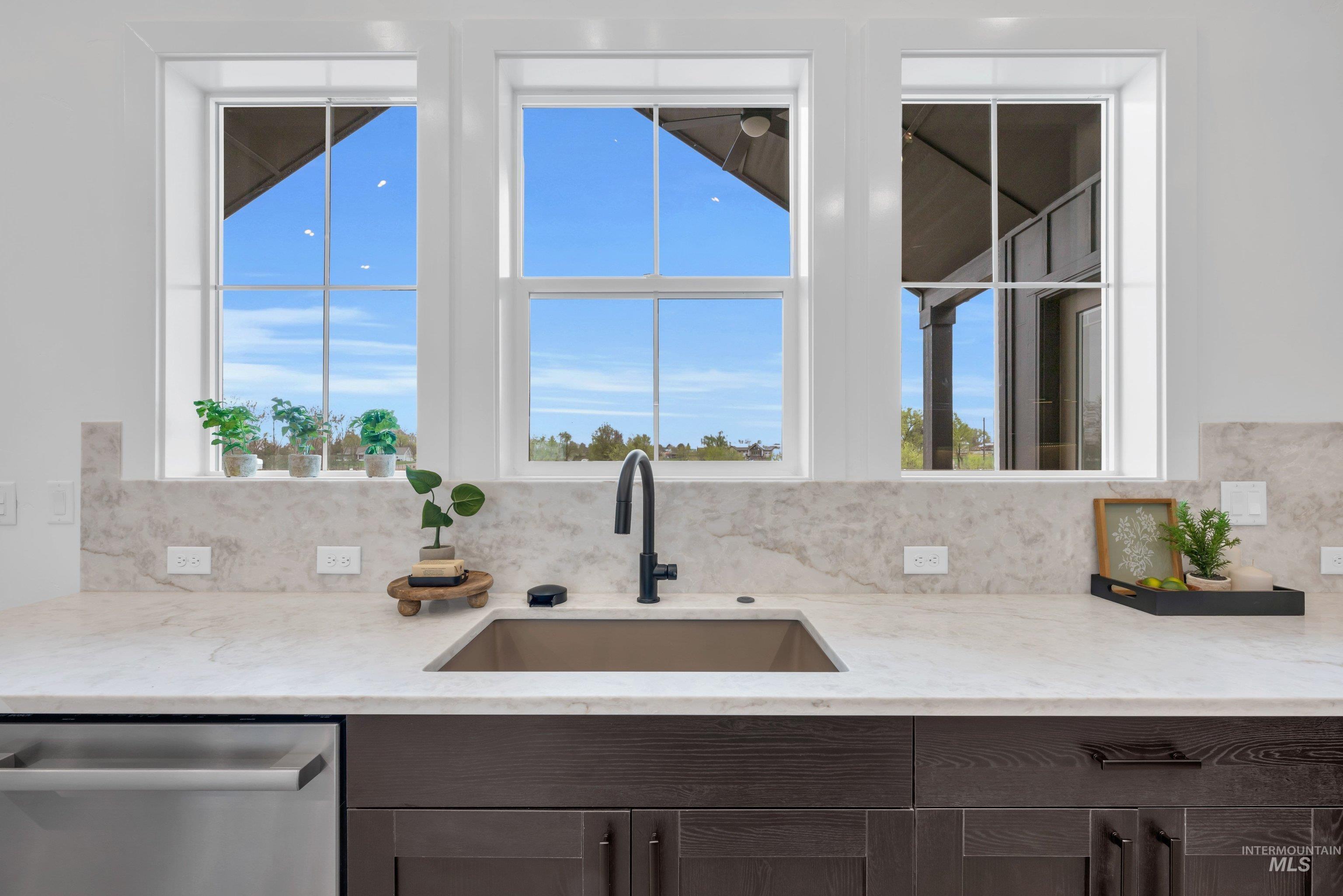 24871 Ardmore Court Caldwell, ID 83607 - Photo 13 of 44 Kitchen featuring light stone countertops, dishwasher, dark wood finish cabinets, and plenty of natural light