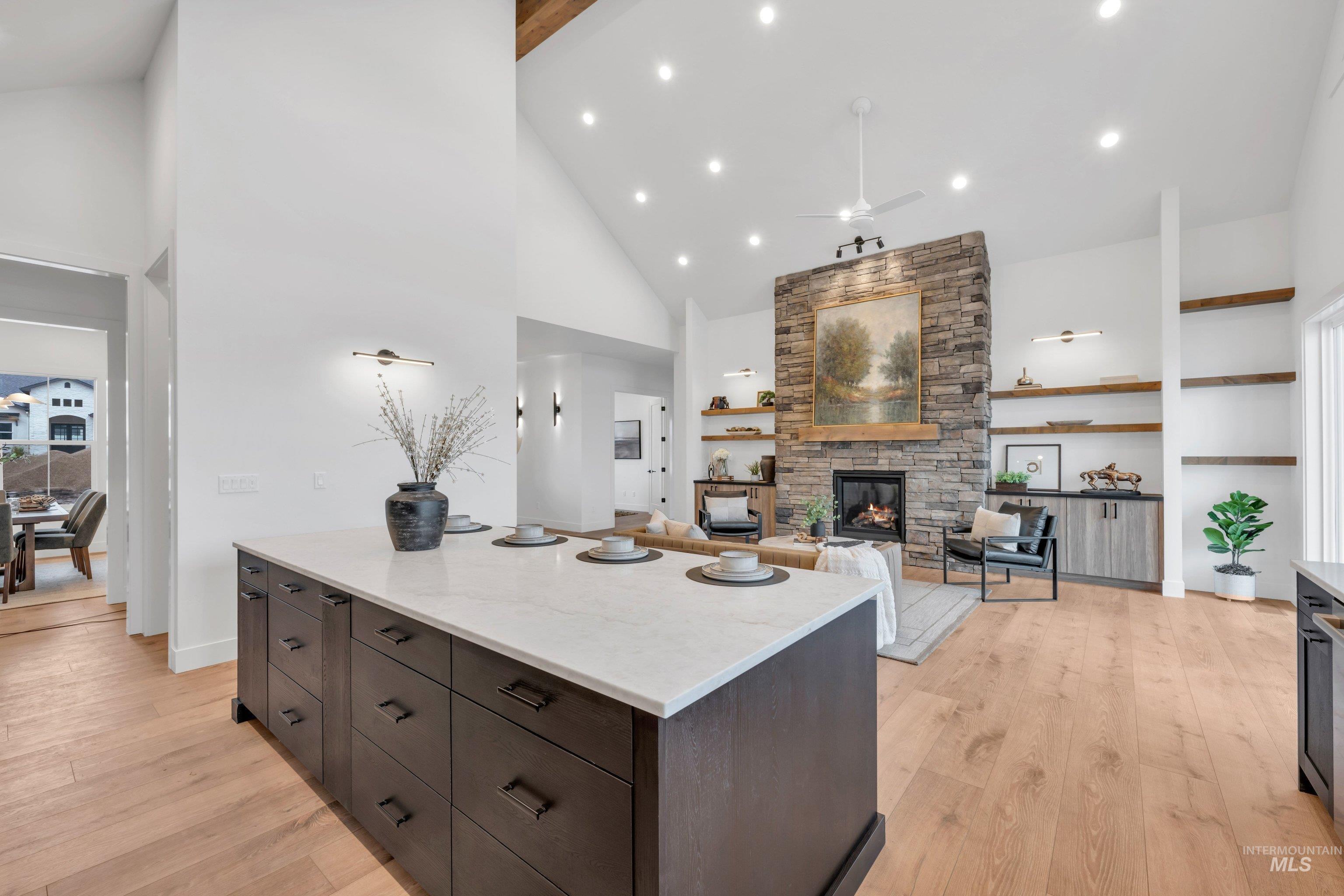 24871 Ardmore Court Caldwell, ID 83607 - Photo 14 of 44 Kitchen with a center island, light wood-type flooring, a stone fireplace, dark wood finish cabinets, and recessed lighting