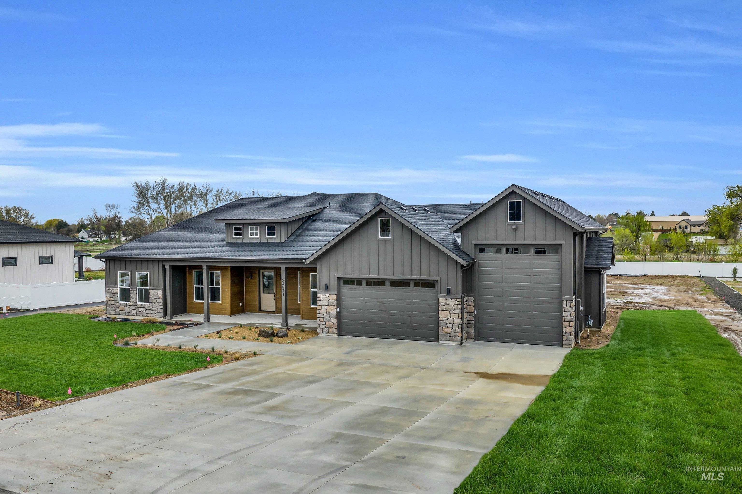24871 Ardmore Court Caldwell, ID 83607 - Photo 2 of 44 Craftsman-style house with covered porch, a front lawn, a garage, concrete driveway, and stone siding