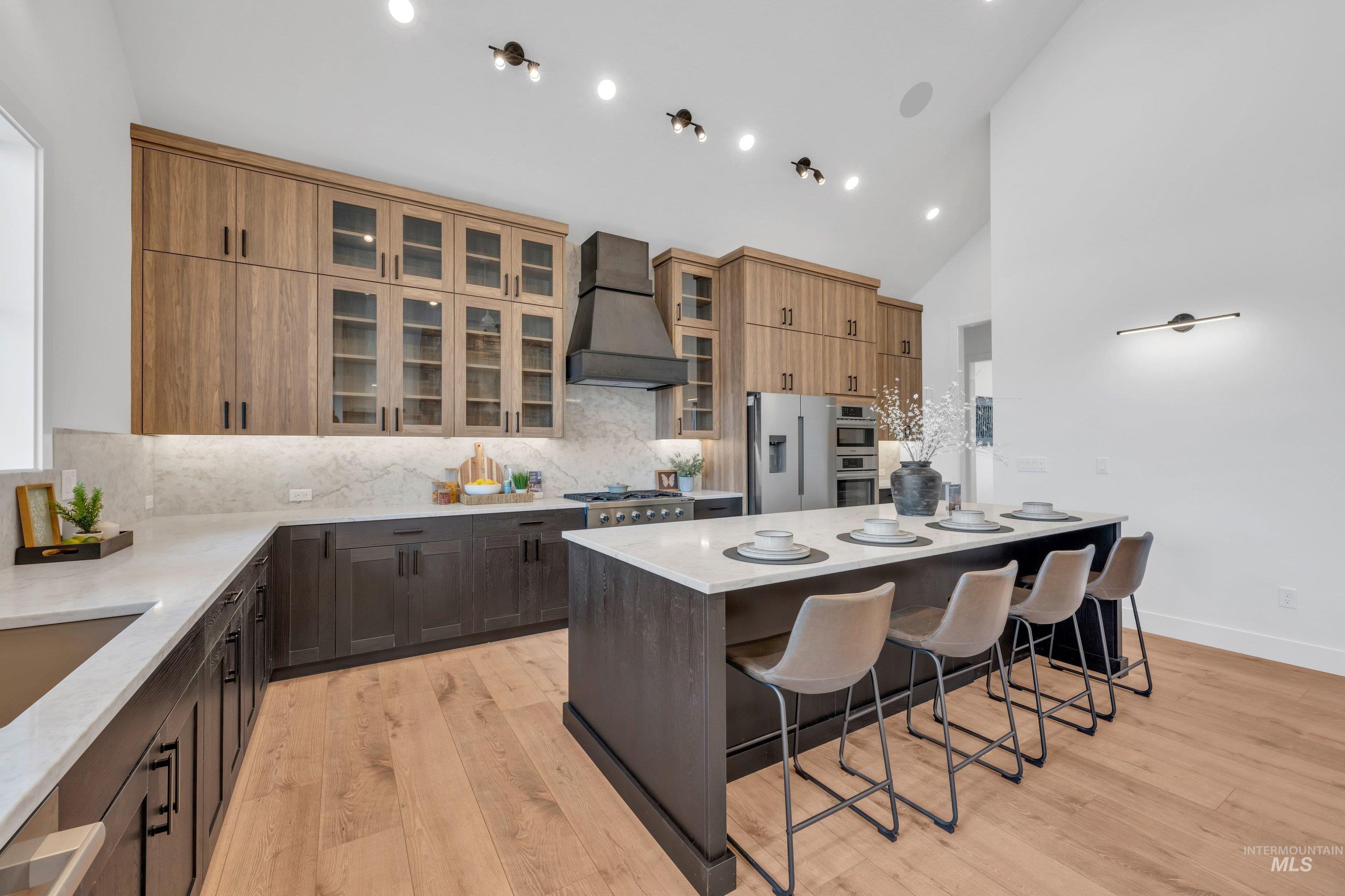 24871 Ardmore Court Caldwell, ID 83607 - Photo 10 of 44 Kitchen with light stone countertops, a kitchen island, a breakfast bar, light wood finished floors, and stainless steel appliances
