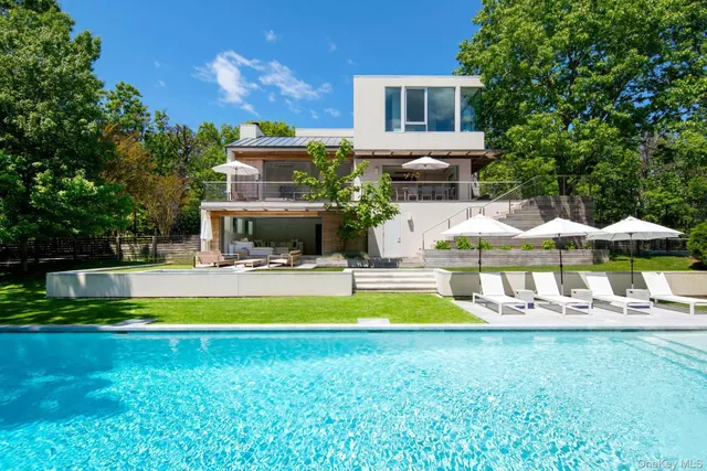 a view of swimming pool with lawn chairs and large trees