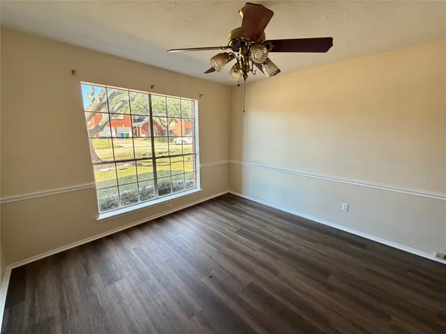 a view of an empty room with wooden floor fireplace and a window