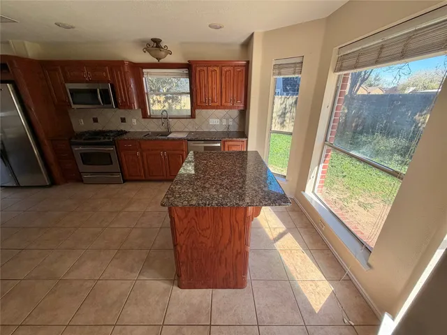 a kitchen with granite countertop a stove a sink and a refrigerator