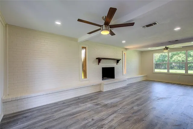 an empty room with windows and fireplace