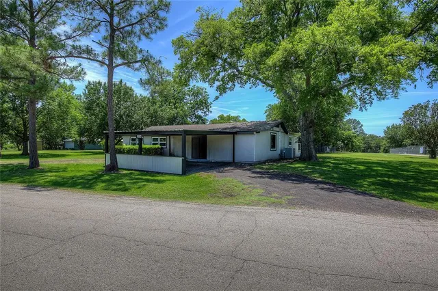 a view of a house with a big yard and large trees
