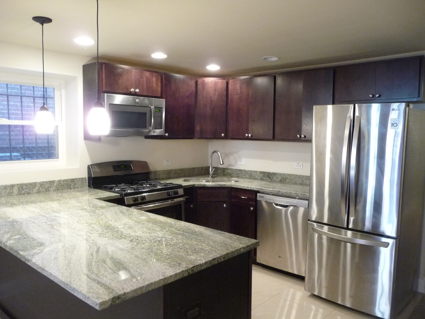 1803 West Superior Street, Unit GDN Chicago, IL 60622 - Photo 2 of 14 a kitchen with kitchen island granite countertop a refrigerator a sink and wooden cabinets
