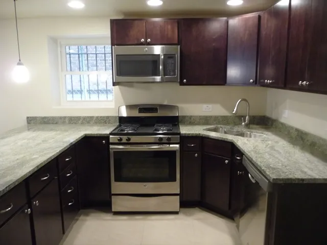 a kitchen with granite countertop wooden cabinets and a stove top oven