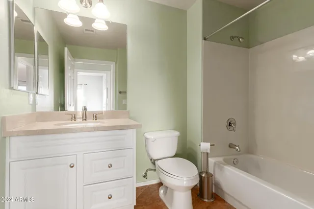 a bathroom with a toilet a sink a mirror a bathtub and vanity