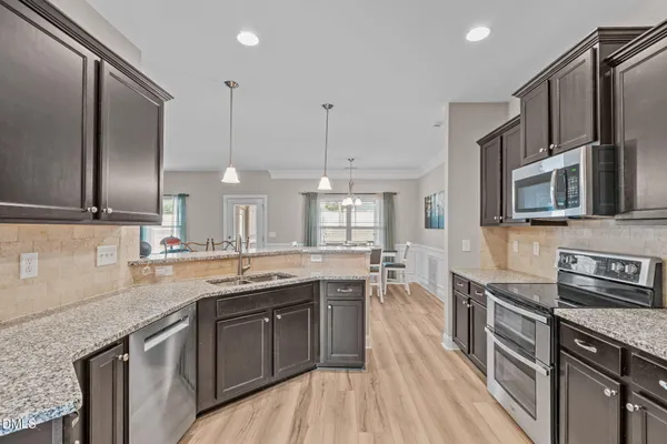 a kitchen with stainless steel appliances granite countertop a sink a stove and a wooden floors