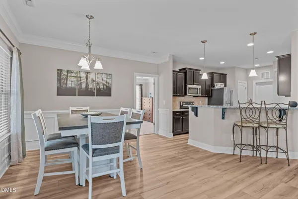 a view of a dining room and livingroom with furniture wooden floor a chandelier