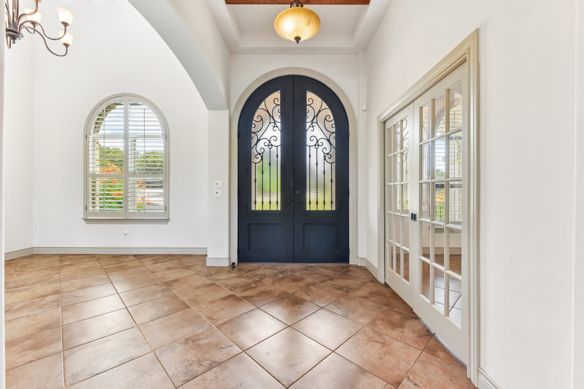 163 Powder Horn Road Bastrop, TX 78602 - Photo 6 of 34 Arched entryways and warm tile flooring create a welcoming entrance foyer with French doors.