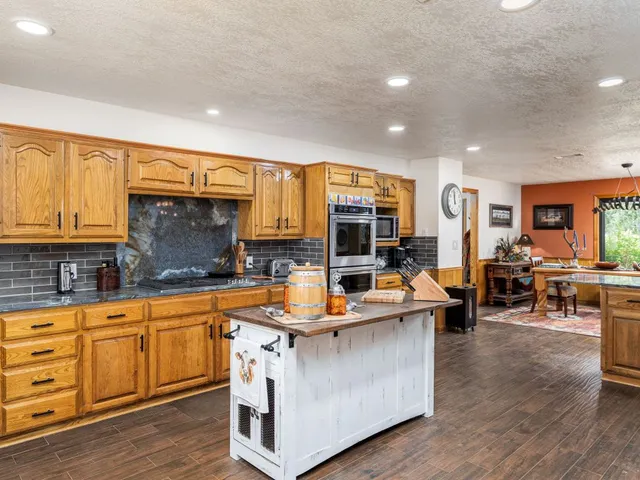 a view of a kitchen counter top space with granite countertop wooden floor stainless steel appliances and cabinets