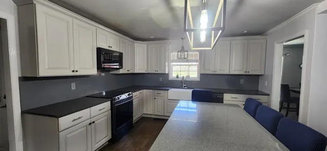 a kitchen with stainless steel appliances granite countertop white cabinets and a stove