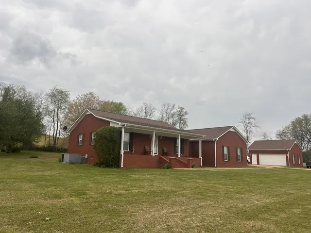 a view of a yard in front of a house with large trees