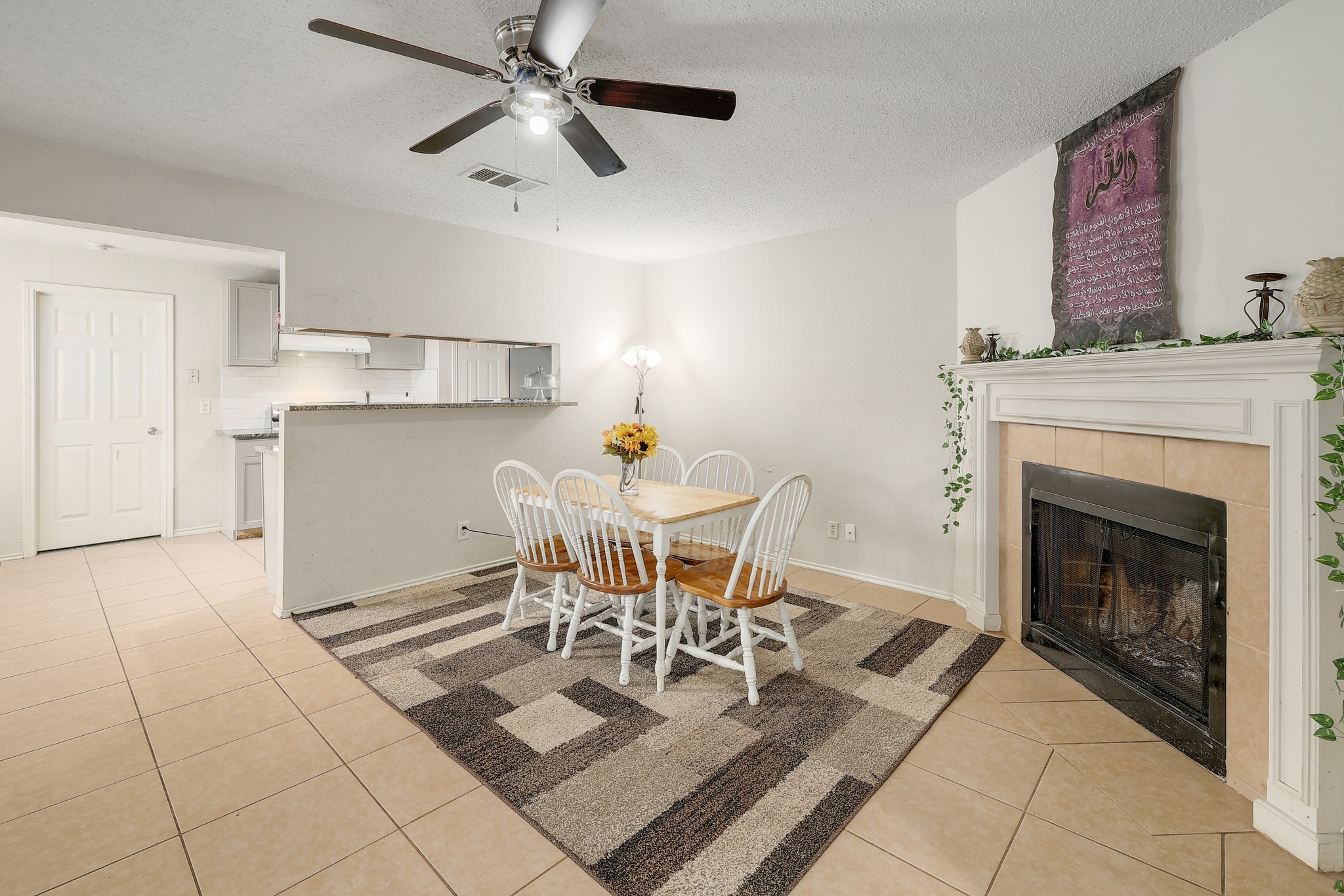 9901 Parliament House Road Austin, TX 78729 - Photo 17 of 40 Dining room with light tile patterned flooring, a textured ceiling, a tiled fireplace, and ceiling fan