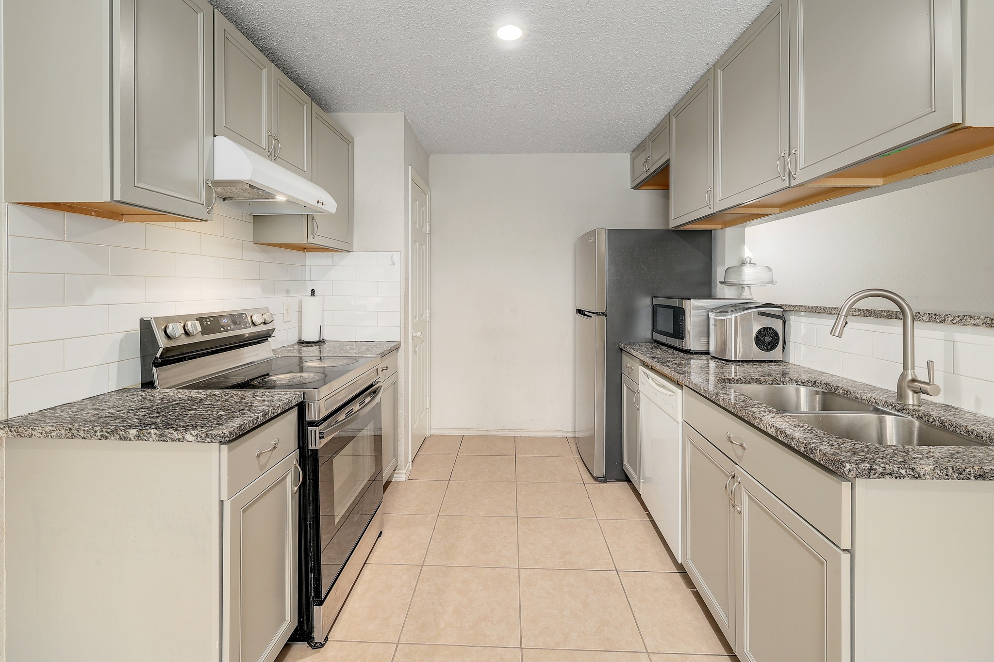 9901 Parliament House Road Austin, TX 78729 - Photo 21 of 40 Kitchen with stainless steel appliances, dark stone countertops, a textured ceiling, light tile patterned flooring, and gray cabinets